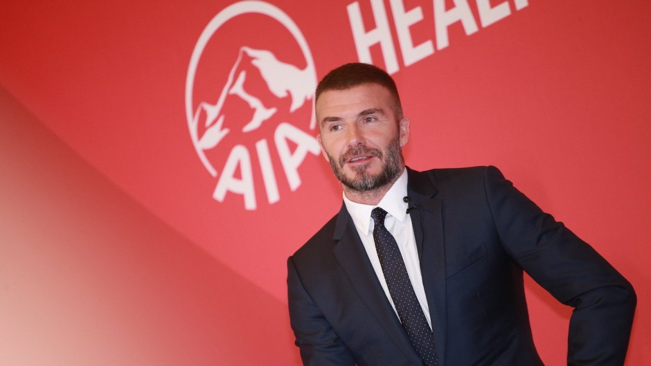 David Beckham wearing a suit, with a red back drop