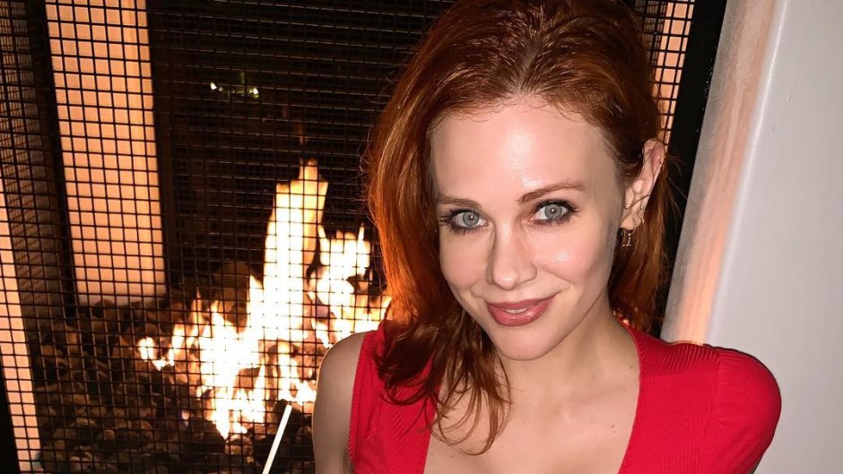 Maitland Ward Wearing a Red Dress in Front of the Fire Place