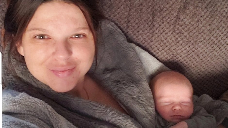 amy duggar king smiling at camera holding a sleeping dax ryan