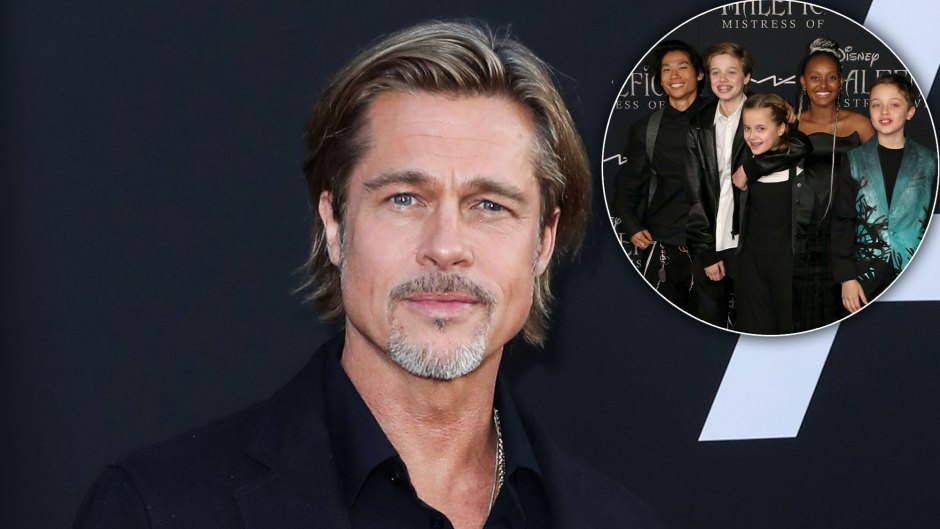 Brad Pitt Wearing Navy Suit With Navy SHirt Looking At Cammera' Inset Jolie- Pitt Kids