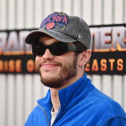 Pete Davidson wears a blue track jacket, baseball cap and sunglasses